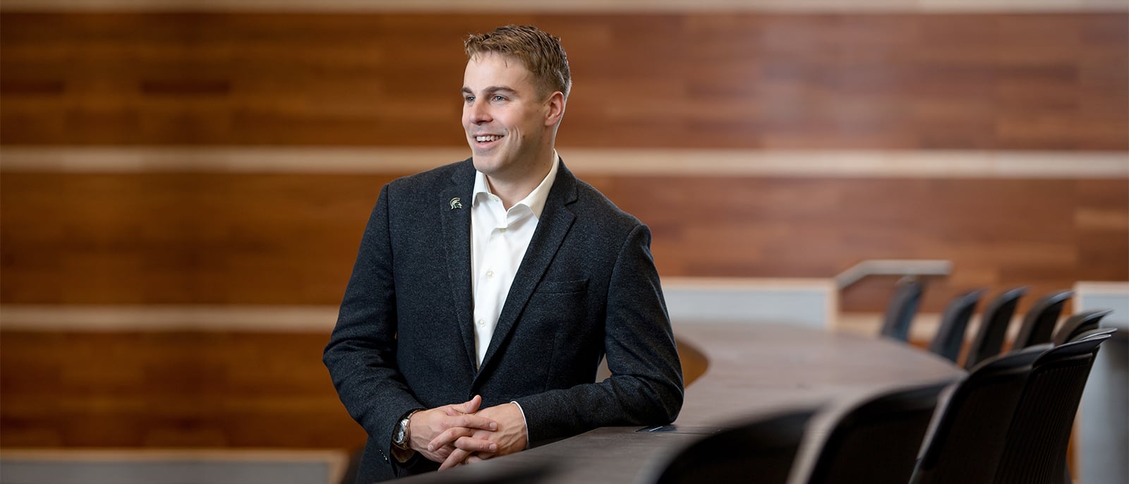 Full-Time MBA student Travis Martin leaning on desk in tiered classroom