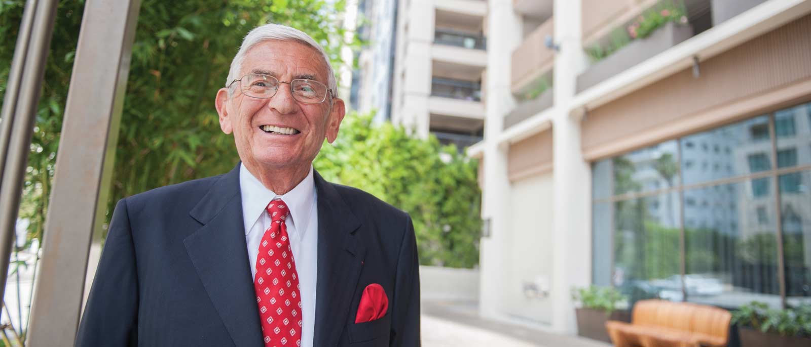 Portrait of business leader and philanthropist Eli Broad, standing outside on a sunny day.