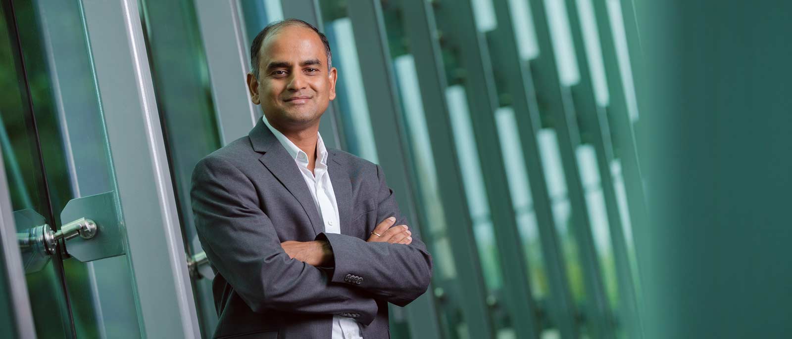 MSU Supply Chain Management Faculty member Sriram Narayanan poses against a backdrop of green glass.
