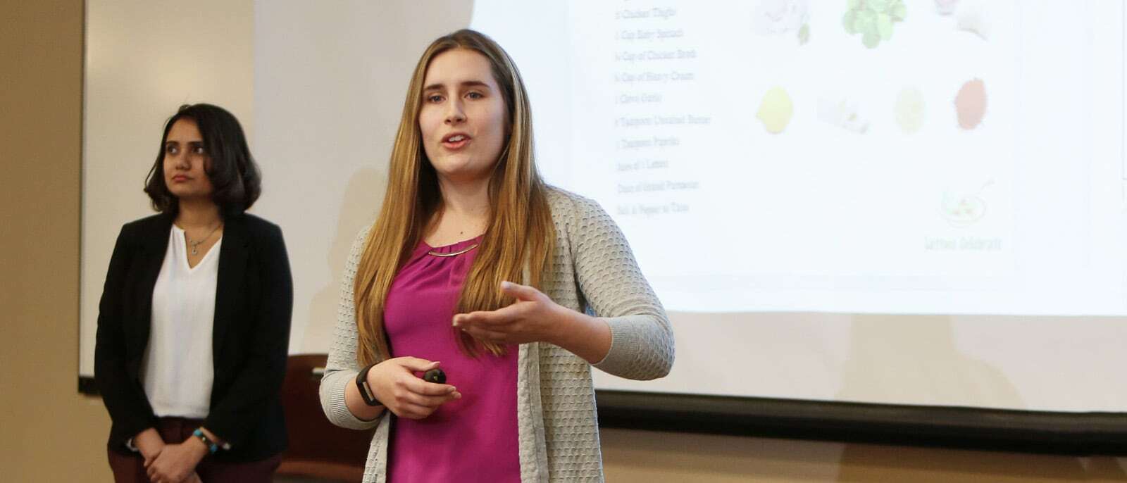 MBA Students presenting with slideshow in background