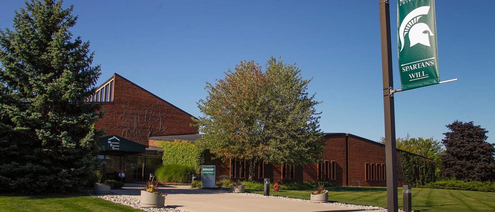 Exterior photo of the front entrance to the Management Education Center (MEC) in Troy, MI on a sunny summer day.