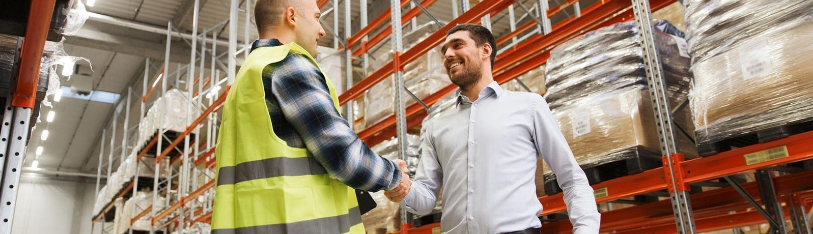 Two men in a warehouse shake hands.
