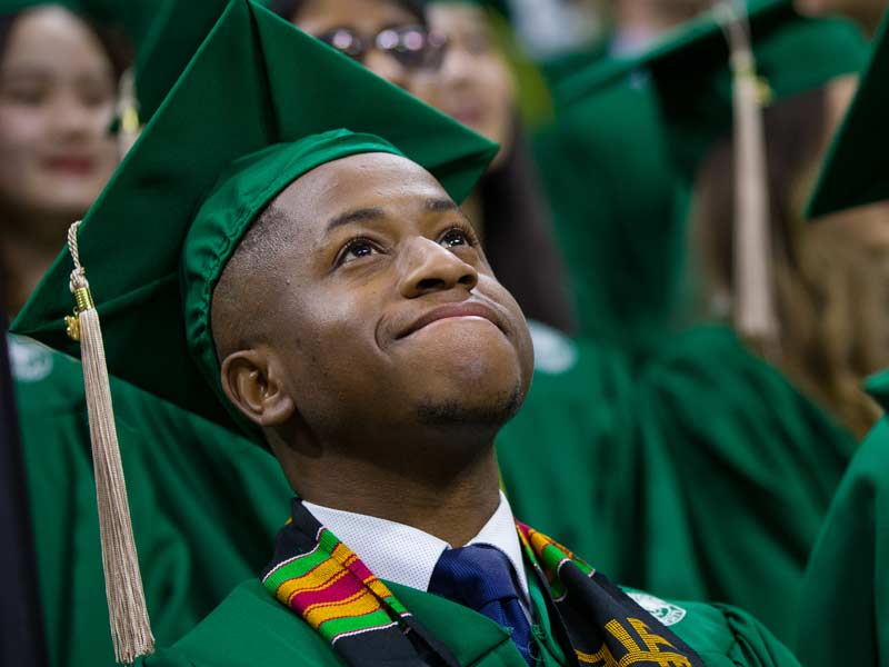 Graduating business school student at MSU looks up, hopeful, at undergraduate commencement ceremony.