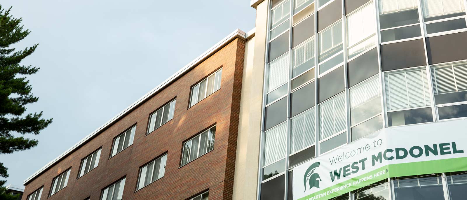 The front facade of McDonel Hall with sunhine reflecting off the wall of windows.
