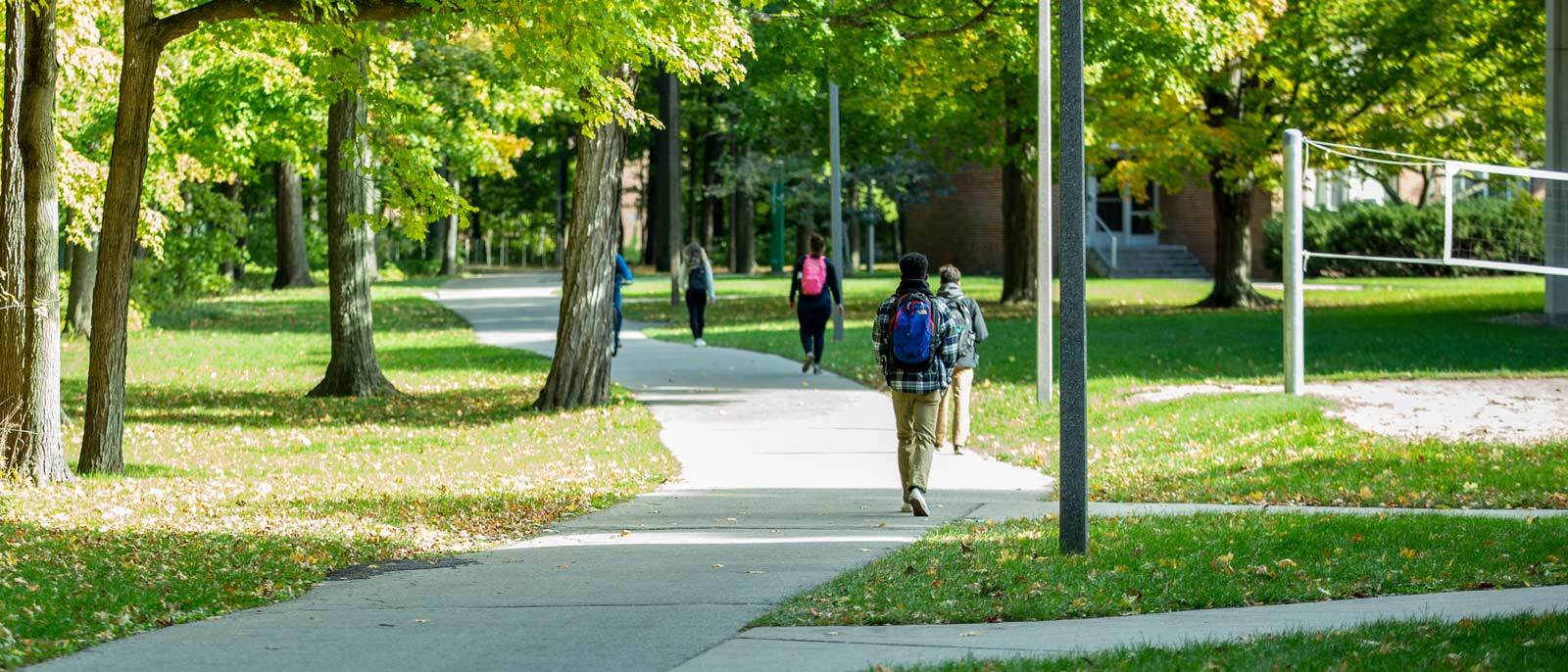 Students walking the path along the Red Cedar River during a sunny summer day.