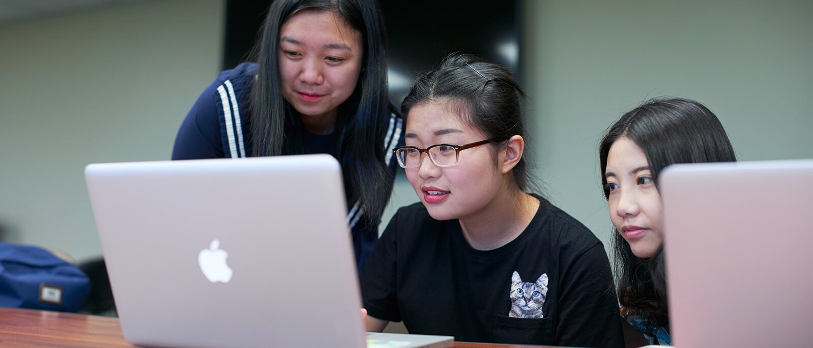 Three undergraduate accounting students working at a table with laptops.