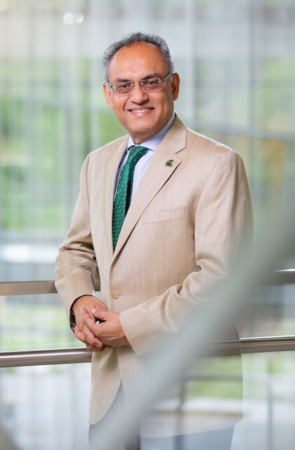 Dean Sanjay Gupta poses inside the atrium of the Edward J. Minskoff Pavilion at the Brand College of Business