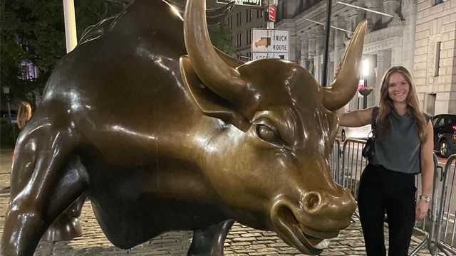Ava Senkowski posing next to Charging Bull statue