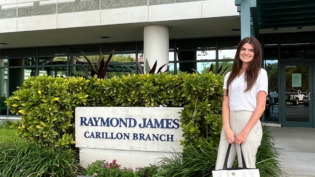 Lauren Dowd standing outside the Raymond James building sign