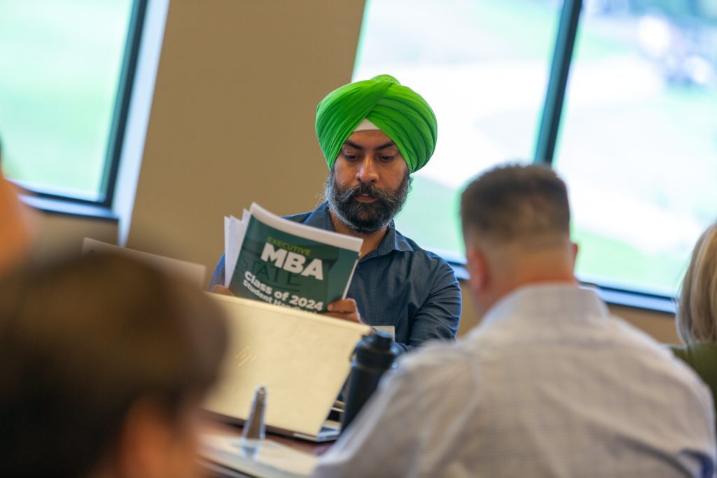 A student reads programmatic paperwork at an Executive MBA orientation event.