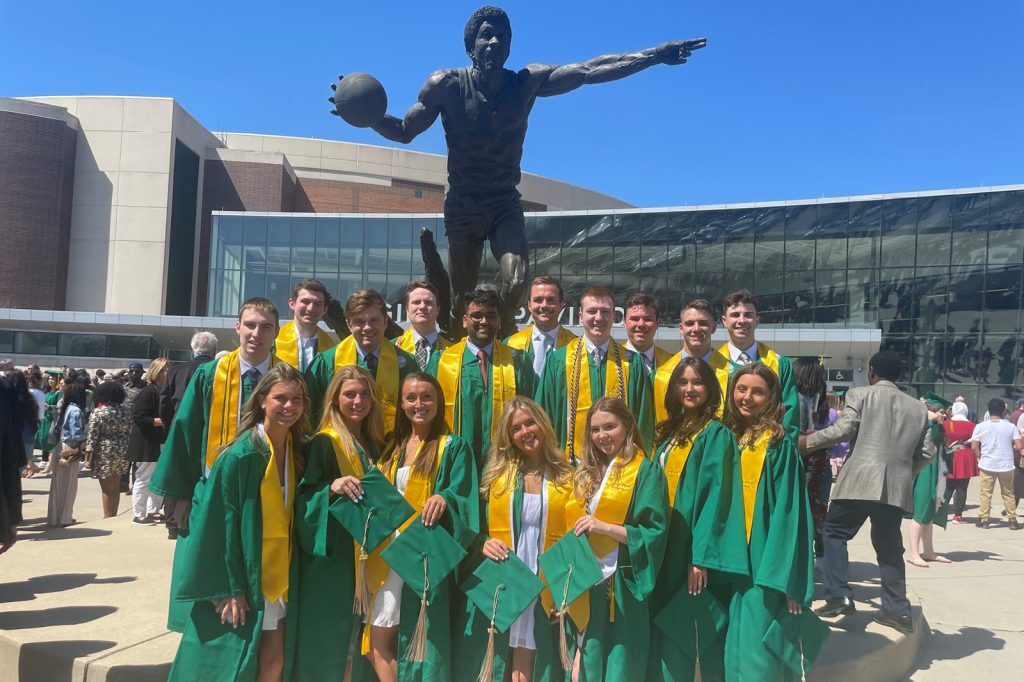 Broad finance students pose for a group picture outside the Breslin Center, in front of the Magic Johnson statue, for commencement.