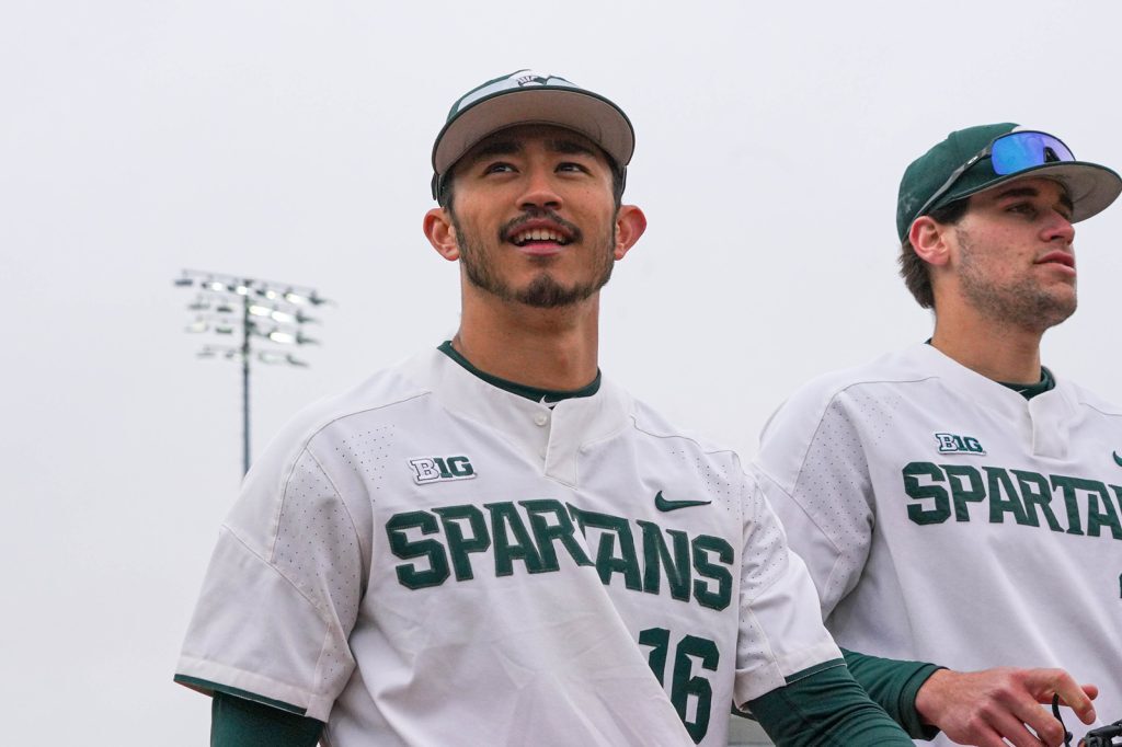Close up of Peter Ahn wearing home Spartan baseball uniform and walking with teammate.
