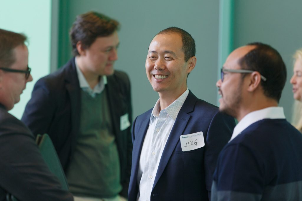 Broad alumnus Jing Wang smiles while speaking with other alumni, faculty and staff at a Broad College event.