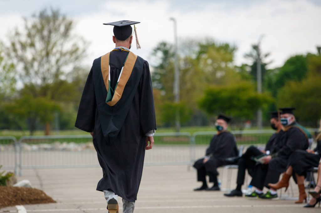 An MSU student wearing academic regalia for the master's commencement ceremony walks away from the camera on graduation day.