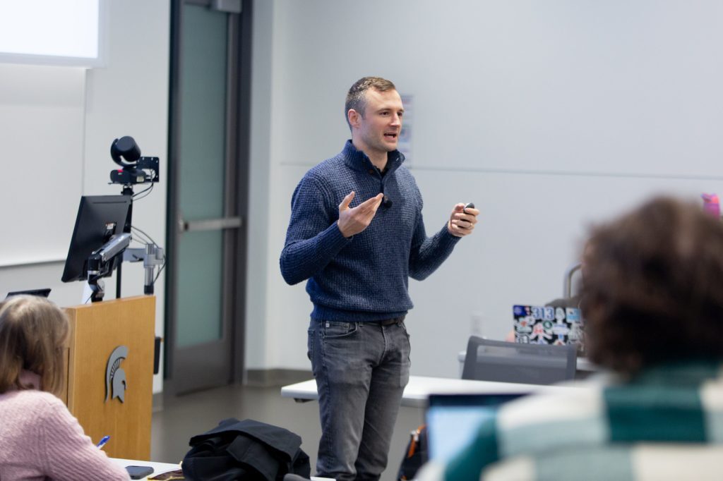 Mike Vichich stands while speaking to a class of students in the Minskoff Pavilion.