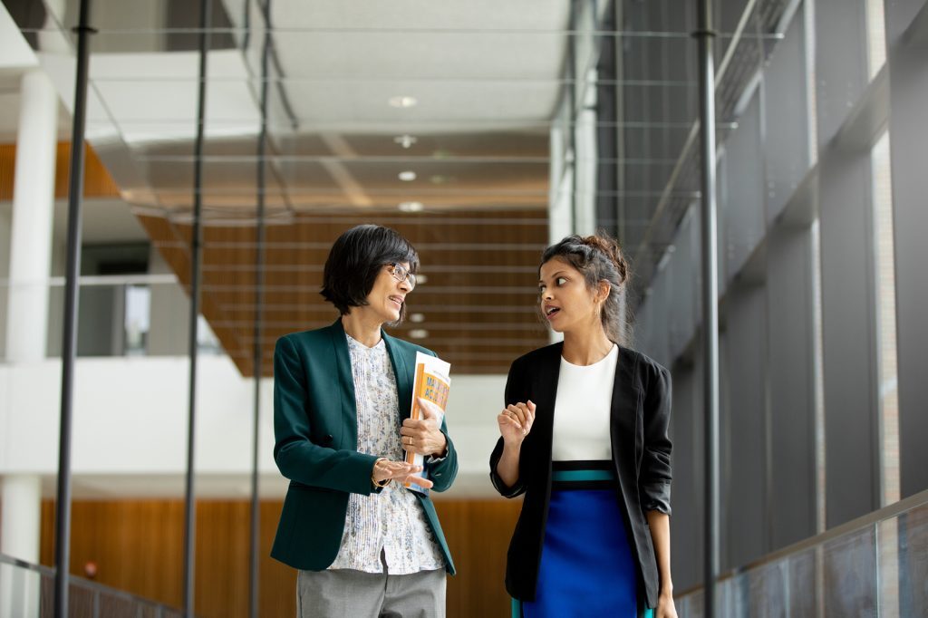 A faculty member and student talk while walking through the Broad College's Minskoff Pavilion.