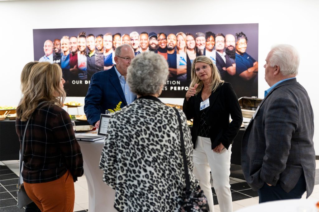 Cheryl Thompson speaks in a group of people at a corporate event.
