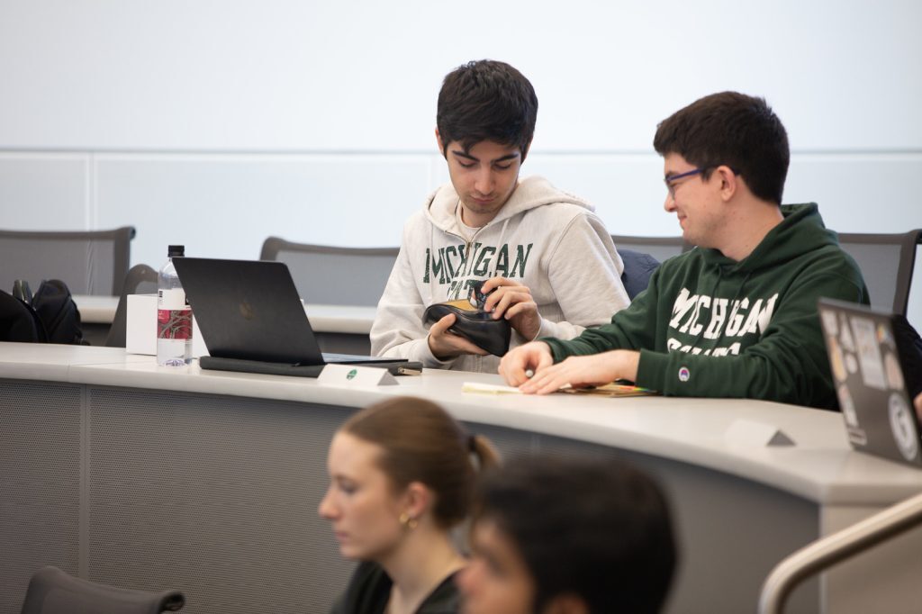 Students look at a shoe while listening to a presentation in class at MSU.