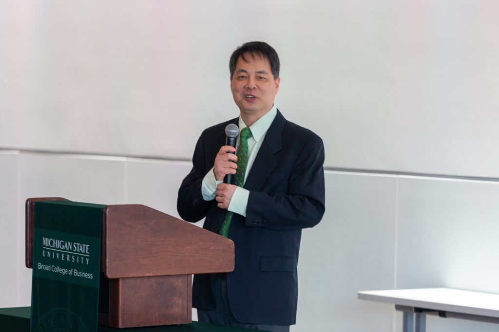 Hayong Yun stands at a podium holding a microphone at the 2023 Student Venture Capital Fund investment celebration.