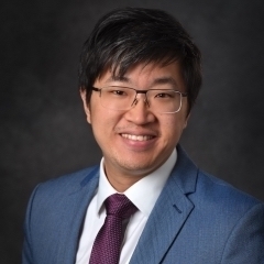 headshot of Stanley Lim, an Asian man wearing a suit and tie and glasses
