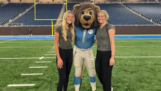 Alex Odenbach and another intern at Ford Field with the Detroit Lions mascot