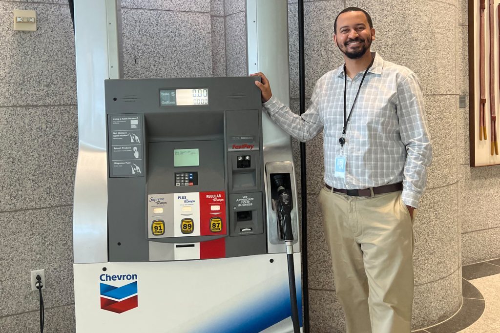Bryce Chatman poses with a vanity Chevron gasoline pump during his 2023 internship experience.