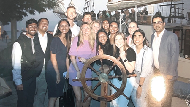 Kareena Boyina posing with other interns holding a ship steering wheel