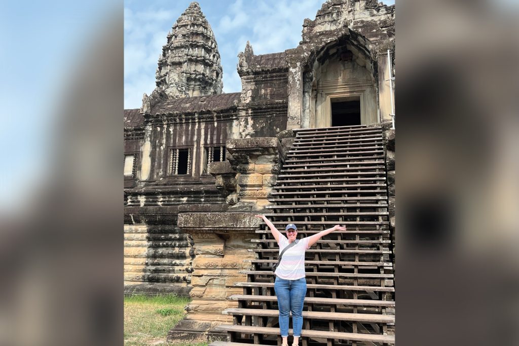 Beth Hammond stands in front of a ruin building in Cambodia.