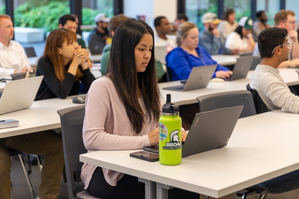 Students fill a classroom and take notes during the guest lecture.
