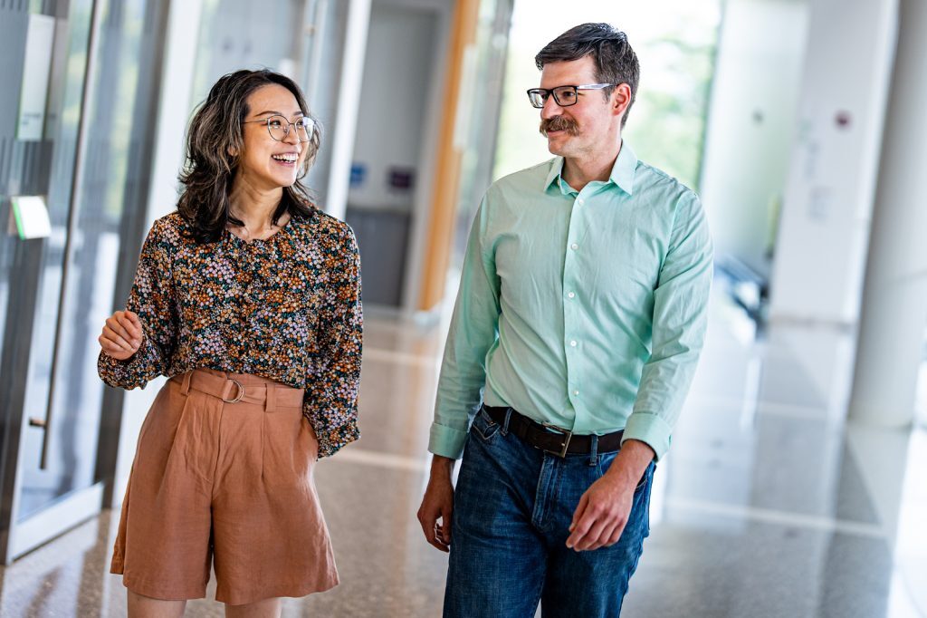 Li Cheng and Jason Miller walk down a pathway in the Minskoff Pavilion.