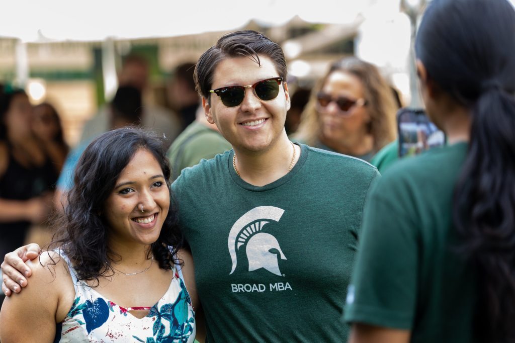 Two Broad Spartans pose for a picture at the 2023 MBA alumni tailgate on MSU's campus.