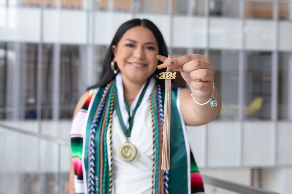 Focus on graduation tassel being held by 2024 Student commencement speaker Diana Talamantes-Valles.