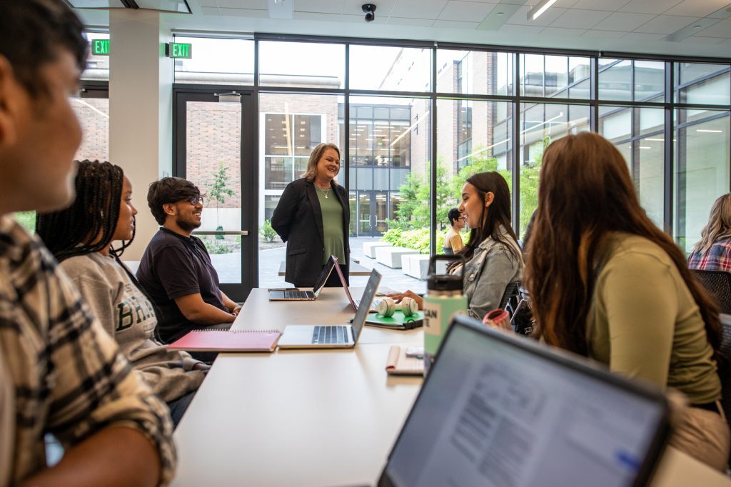 Judith Whipple smiles while interacting with a group of seated students in a classroom in the Minskoff Pavilion.
