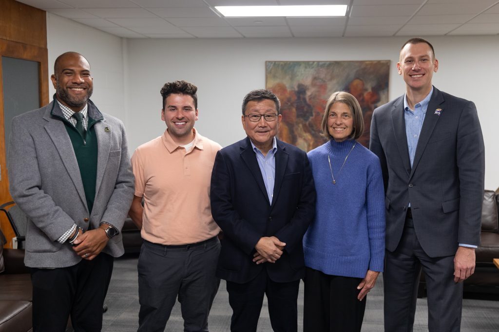 Group of five people standing in a line smiling