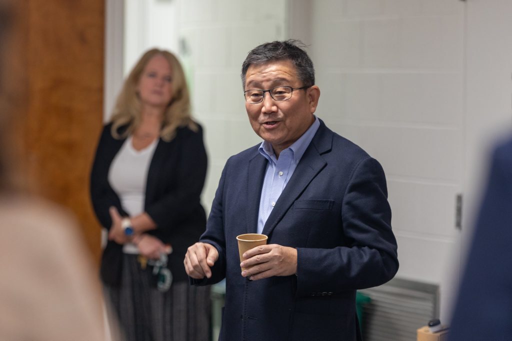 Man speaking to crowd holding cup