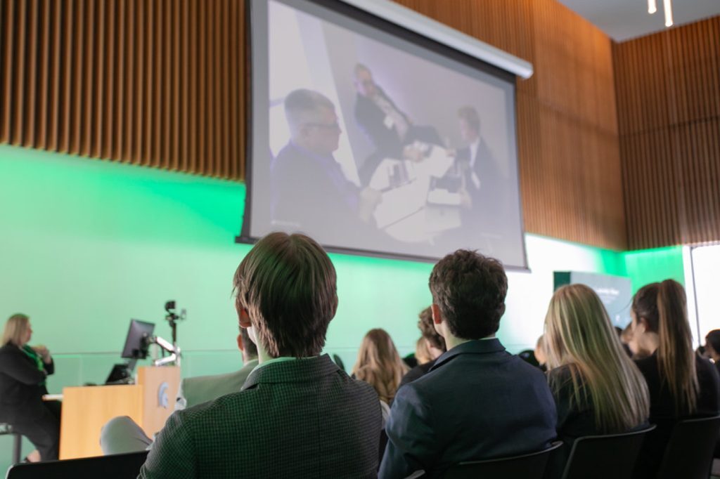 Participants watching interviews on projector screens