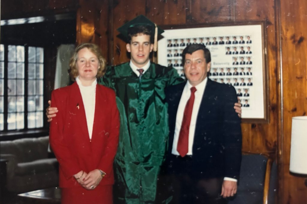 2 people standing with school graduate dressed in cap and gown