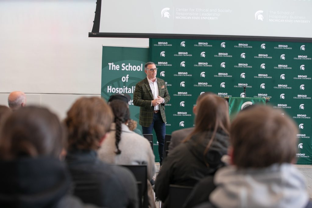 Speaker presenting in front of seated crowd