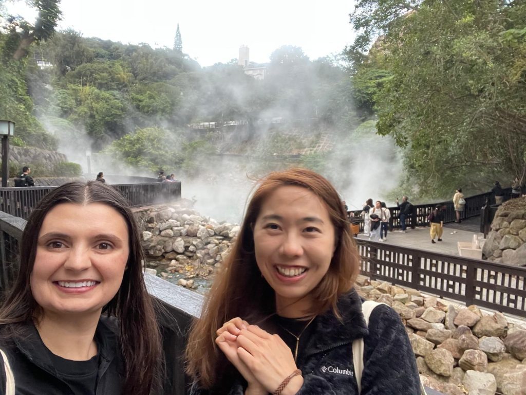 two young women smiling in front of a waterfall.