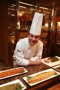 Chef leaning on table with prepared food