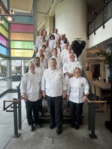Chefs standing on steps smiling 