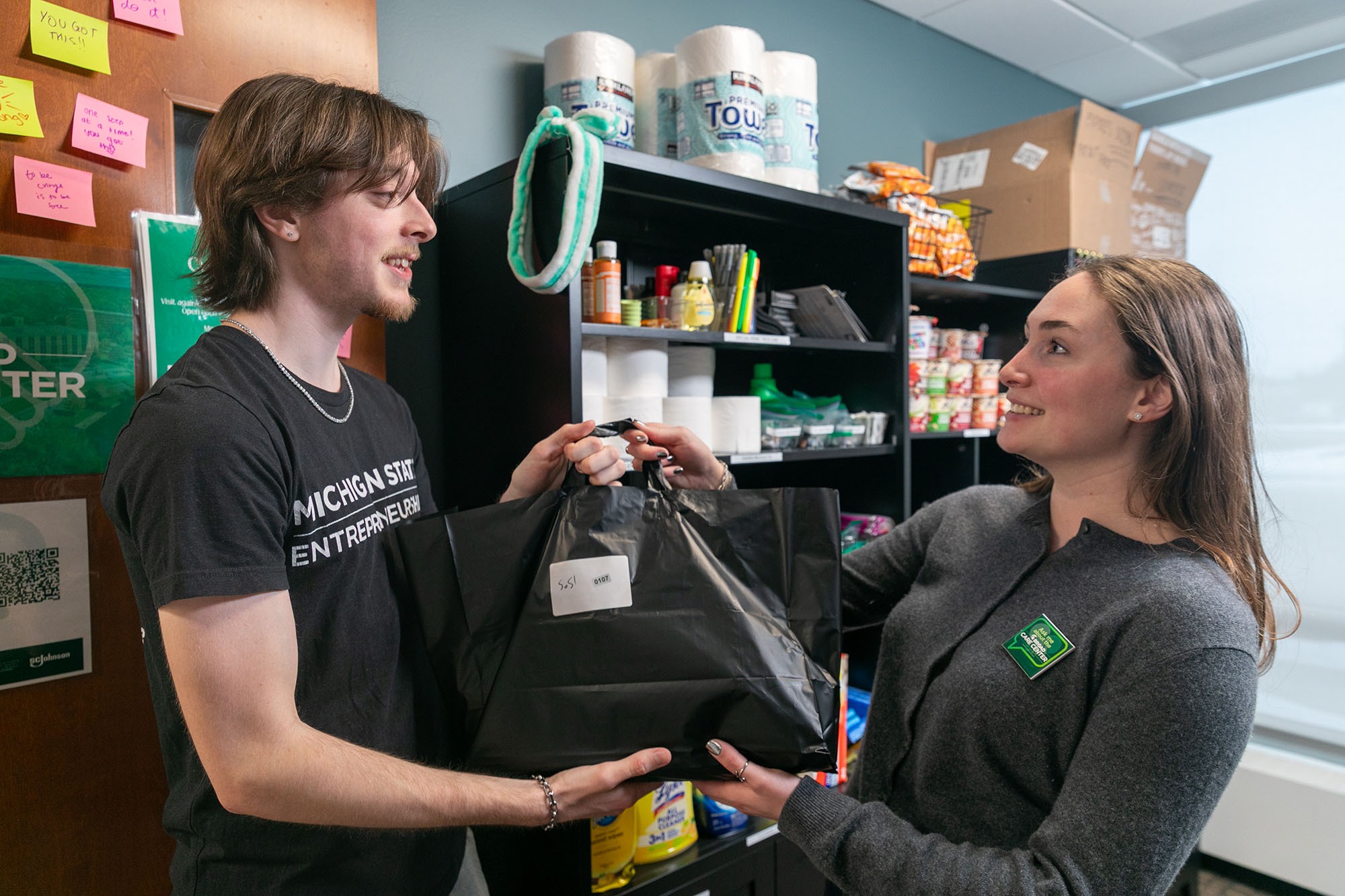 A student. volunteer handing a care center dash bag over to it