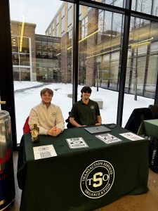 Two people sitting at a table with Transaction Services Organization on the table cloth