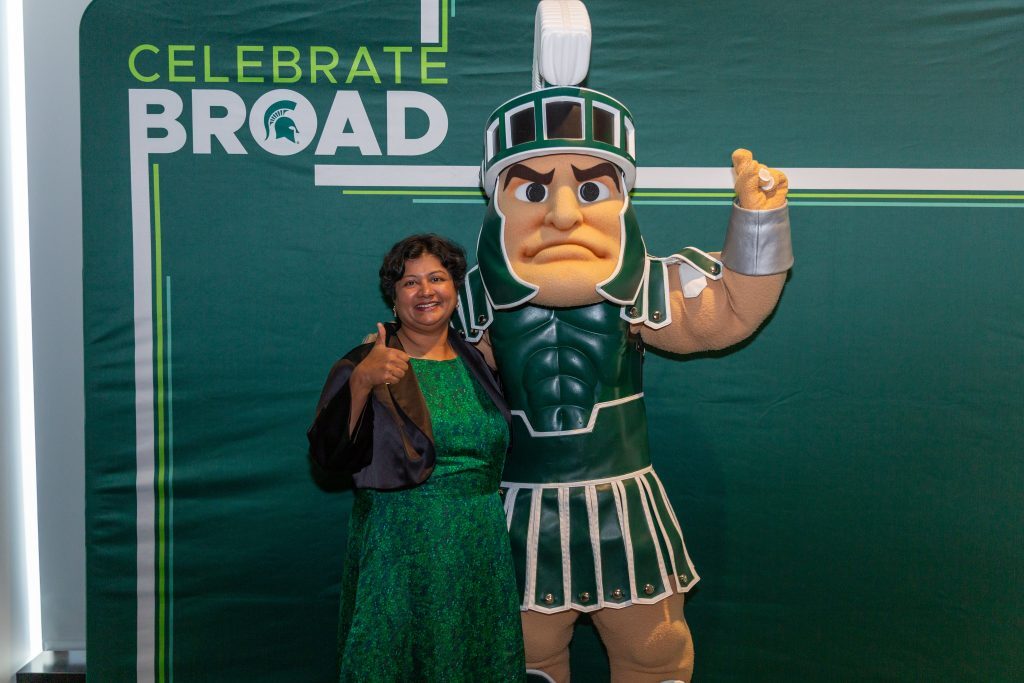An award recipient gives a thumbs up while posing beside the Michigan State Spartan mascot in front of a “Celebrate Broad” backdrop.