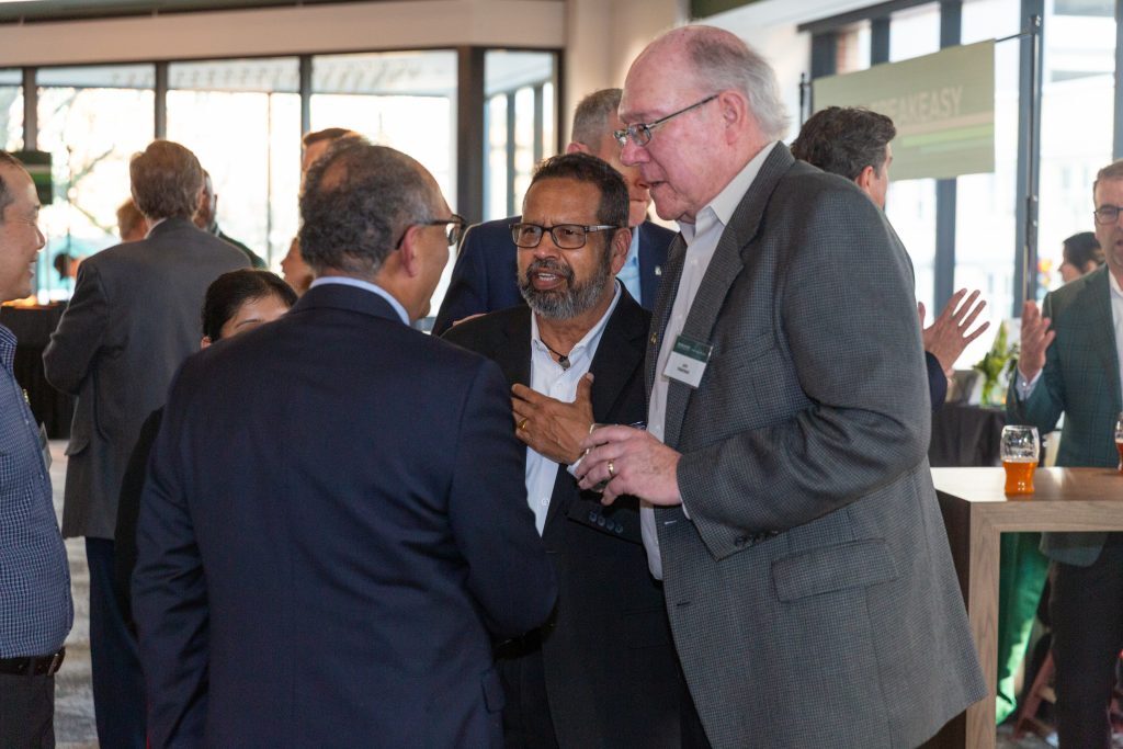 Several attendees engage in conversation during a reception in a bright gathering space.