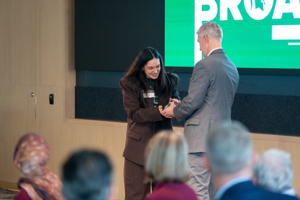 A student receives an award on stage during the Celebrate Broad ceremony as attendees look on.