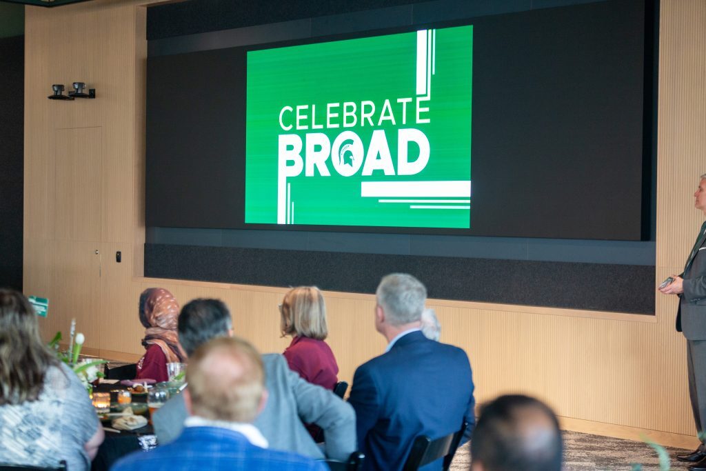 A large digital screen displaying “Celebrate Broad” serves as the focal point of the event space while guests are seated nearby.