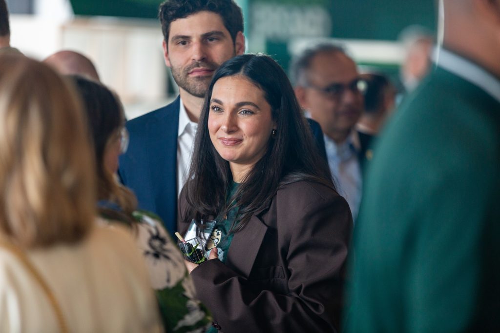 An attendee in a brown suit smiles while conversing with guests during the Celebrate Broad reception.