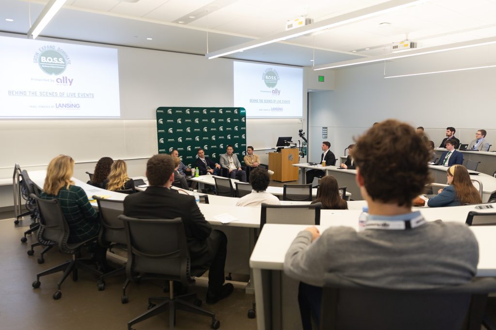 Wide view of a classroom panel event at the Broad College of Business, with students seated in a lecture hall listening to speakers at the front.