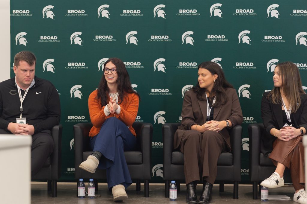 Panel of four participants seated on stage in front of a Broad College of Business backdrop, engaging in a discussion.